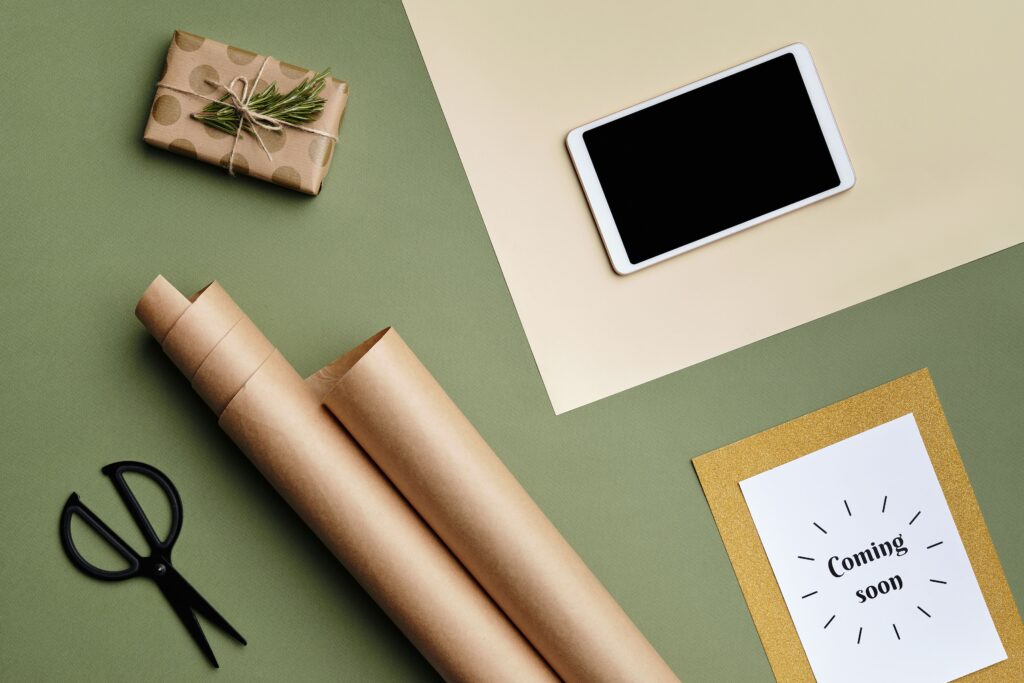 Overhead view of craft paper, tablet, and scissors in a creative flat lay composition.