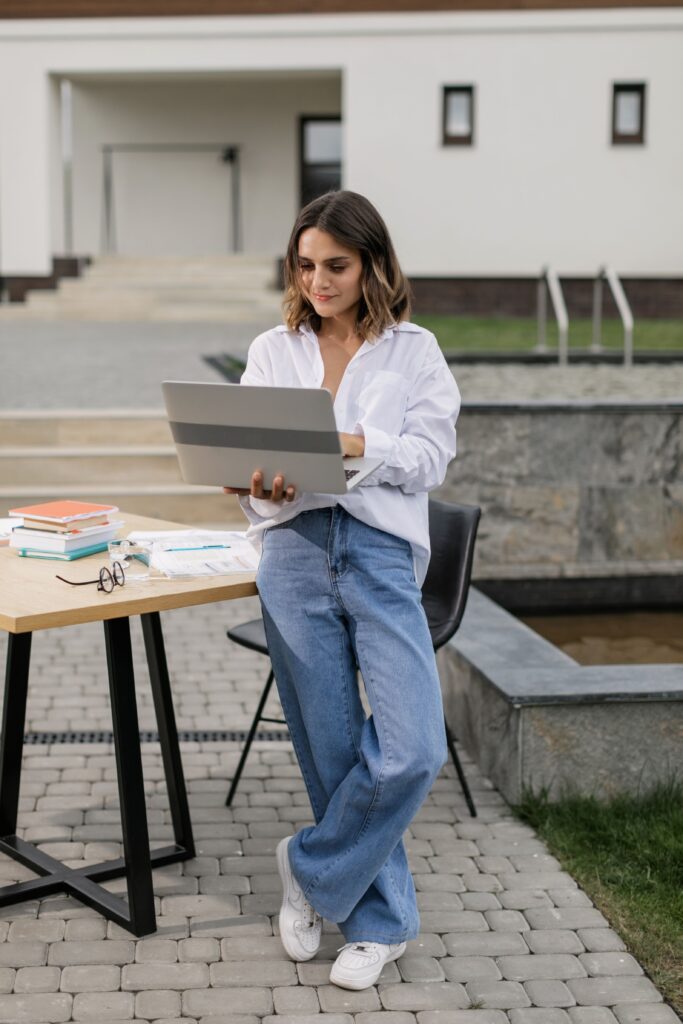 A woman uses a laptop on a table outdoors, embracing a digital nomad lifestyle.